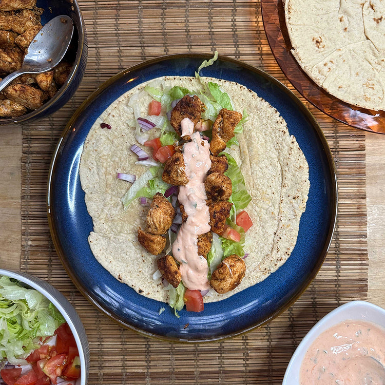 Picture - A tortilla wrap open on a plate. It is generously filled with grilled chicken, lettuce, onion, tomato & low carb chilli mayonnaise.  