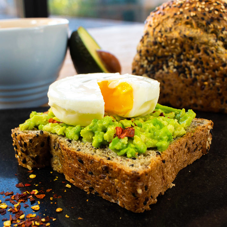 Picture - A close up of a thick slice of seeded low carb bread smothered in smashed avocado, topped with chilli flakes and a poached egg. 