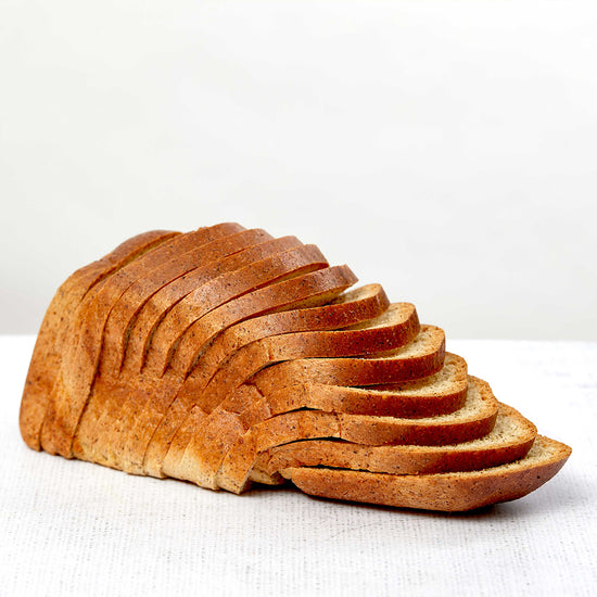 Picture - A low carb loaf of sliced bread with all the slices gently falling away from the loaf in a waterfall effect. All on a plain white background. 