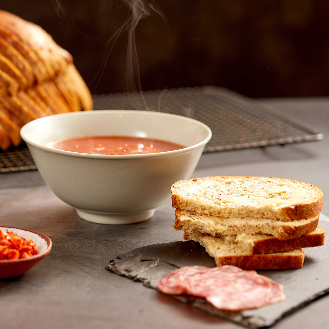 Picture - Two slices of low carb bread sat neatly next to a big bowl of steamy tomato soup. The ideal low carb lunch idea. 