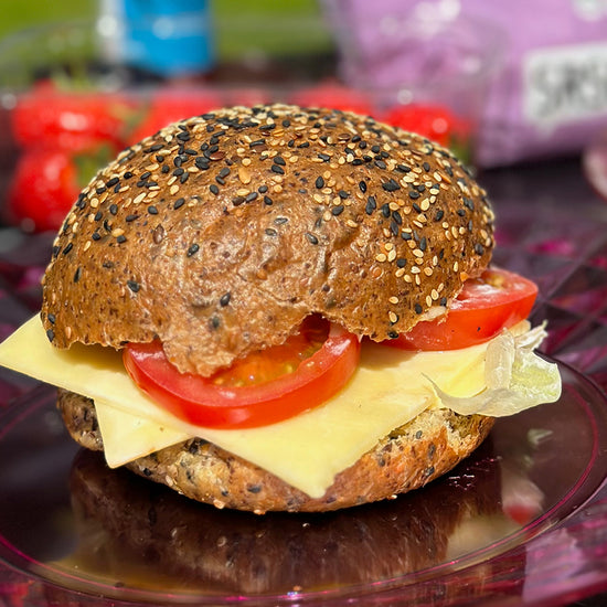 Picture - A low carb seeded roll plated up outside on a sunny day. The rolls is filled with cheese and tomato making a great healthy low calorie lunch. 