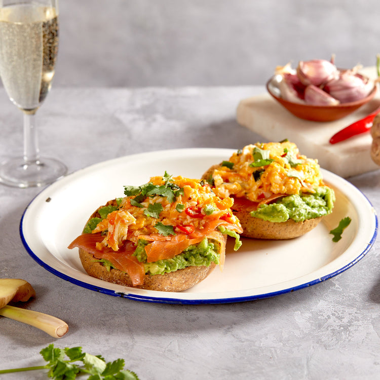 Picture - A low carb roll sliced open with really tasty smoked salmon and scrambled egg layered on top. The rolls is on a plate on a dining room table. 